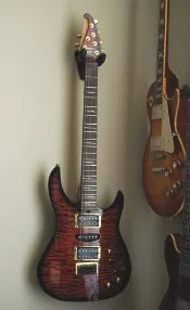 A flame-top guitar hanging beside a Les Paul