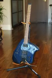 A blue guitar with a sculpted body on a stand