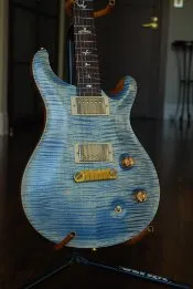 A blue quilt-top guitar on a stand
