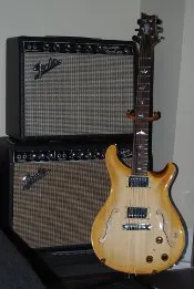 A semi-hollow guitar in front of Fender amps