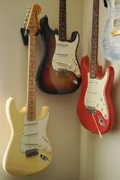 Three Stratocasters hanging on the wall