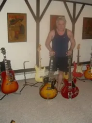 Jan standing behind a 1961 Gibson ES-335 and ES-175, with a Gibson Hummingbird acoustic nearby