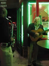 Jan playing acoustic guitar on a street at night in Tampa